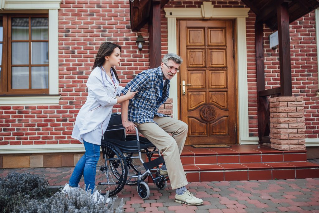 senior-man-sitting-wheelchair-with-smiling-nurse-takes-care-discussion-cheer-garden-nursing-home